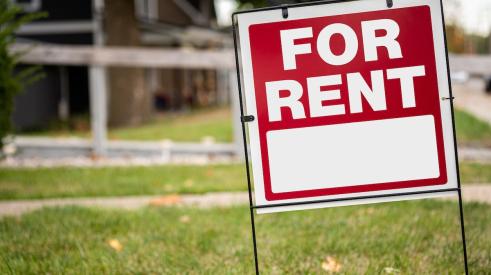 Red and white 'for rent' sign on residential lawn