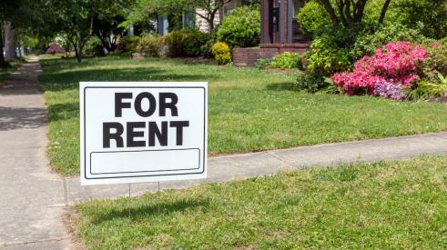 For rent sign in the lawn outside of residential house