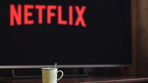 TV with Netflix title screen on, with mug on tabletop