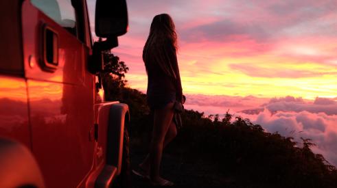 Person looking over land at sunset with Jeep Wrangler