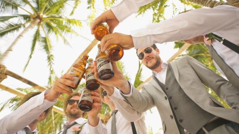 Group of men clinking beer bottles