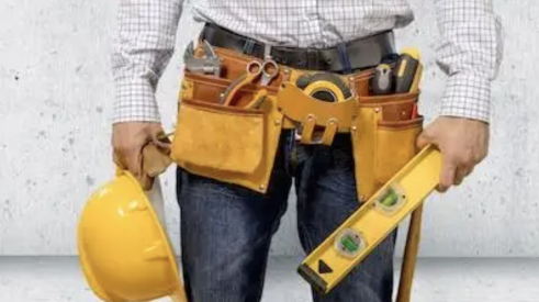 man wearing toolbelt and holding a hard hat and level