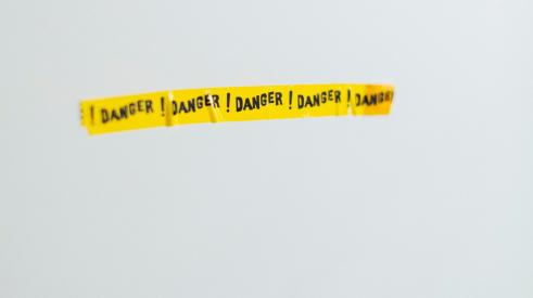 Danger yellow tape on grey wall