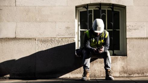 Construction worker looking at phone on break