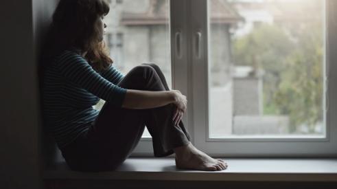 Young woman looking sad while gazing out of window
