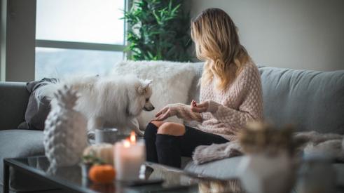 Millennial woman at home sitting on the couch with her dog