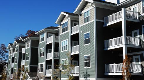 Exterior of gray multifamily apartment building with balconies