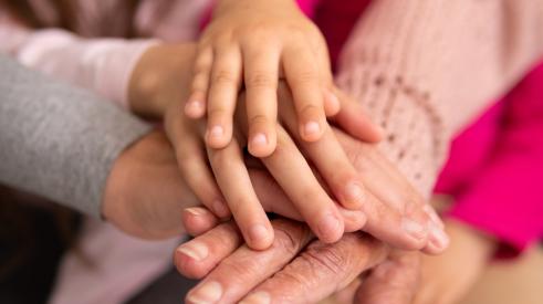 Grandmother's hands covered by younger generations' hands