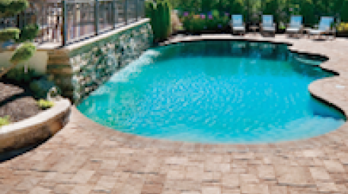 Panorama segmental pavers from Pavestone surround an organically shaped swimming pool.