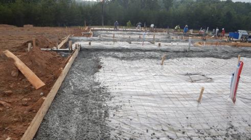 Work in progress on a slab-on-grade concrete foundation with rebar and poured concrete 