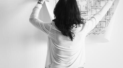Woman hanging up floorplans on wall