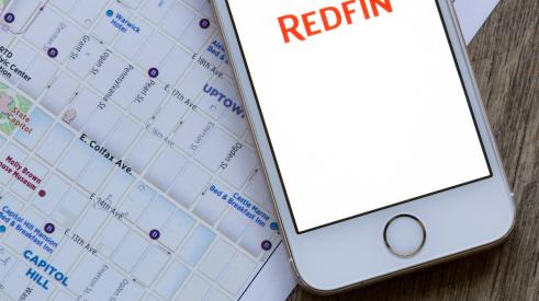 Redfin app open on iPhone next to housing market map