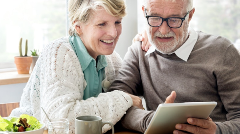 senior couple in kitchen looking at tablet together