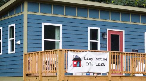 Small blue house with tiny house banner out front