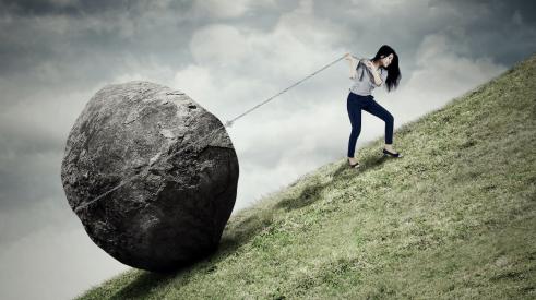 Woman pulling boulder uphill