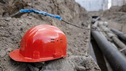 Red construction hard hat in trench 