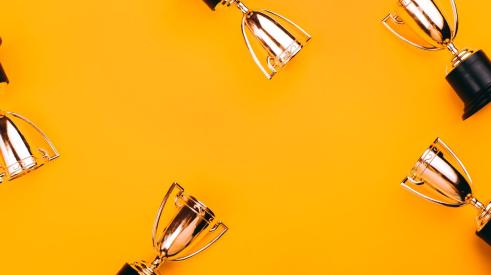 Golden trophies against orange background for winning a competition