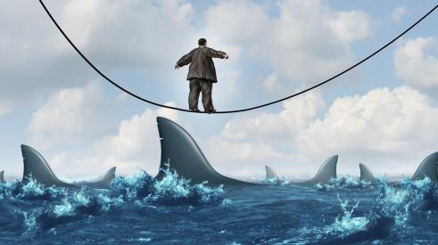 Man on tightrope over shark-infested water