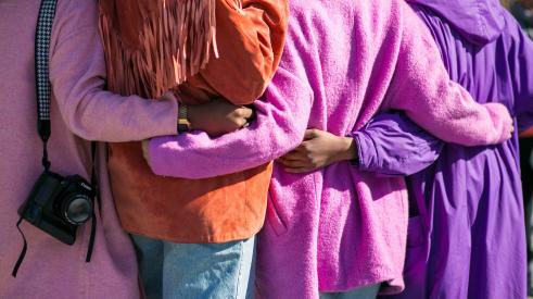 Women hugging with brightly colored coats on