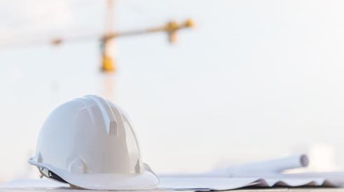 White hard hat and paper construction plans on job site