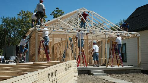 Construction crew framing new house with timber