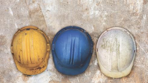 Yellow, blue, and white construction hard hats in a row