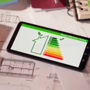 Energy-efficiency rating showing on tablet with house plans in background