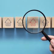 Magnifying glass over wooden block market with house outline