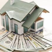 Small house model on stack of cash