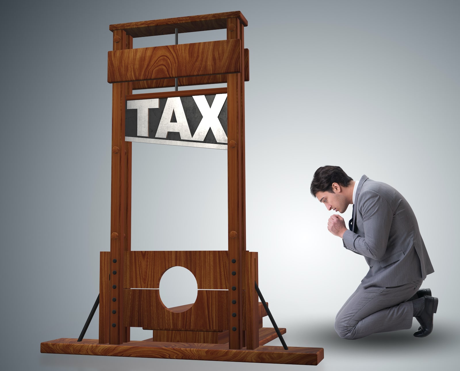 Man kneeling beside tax guillotine 