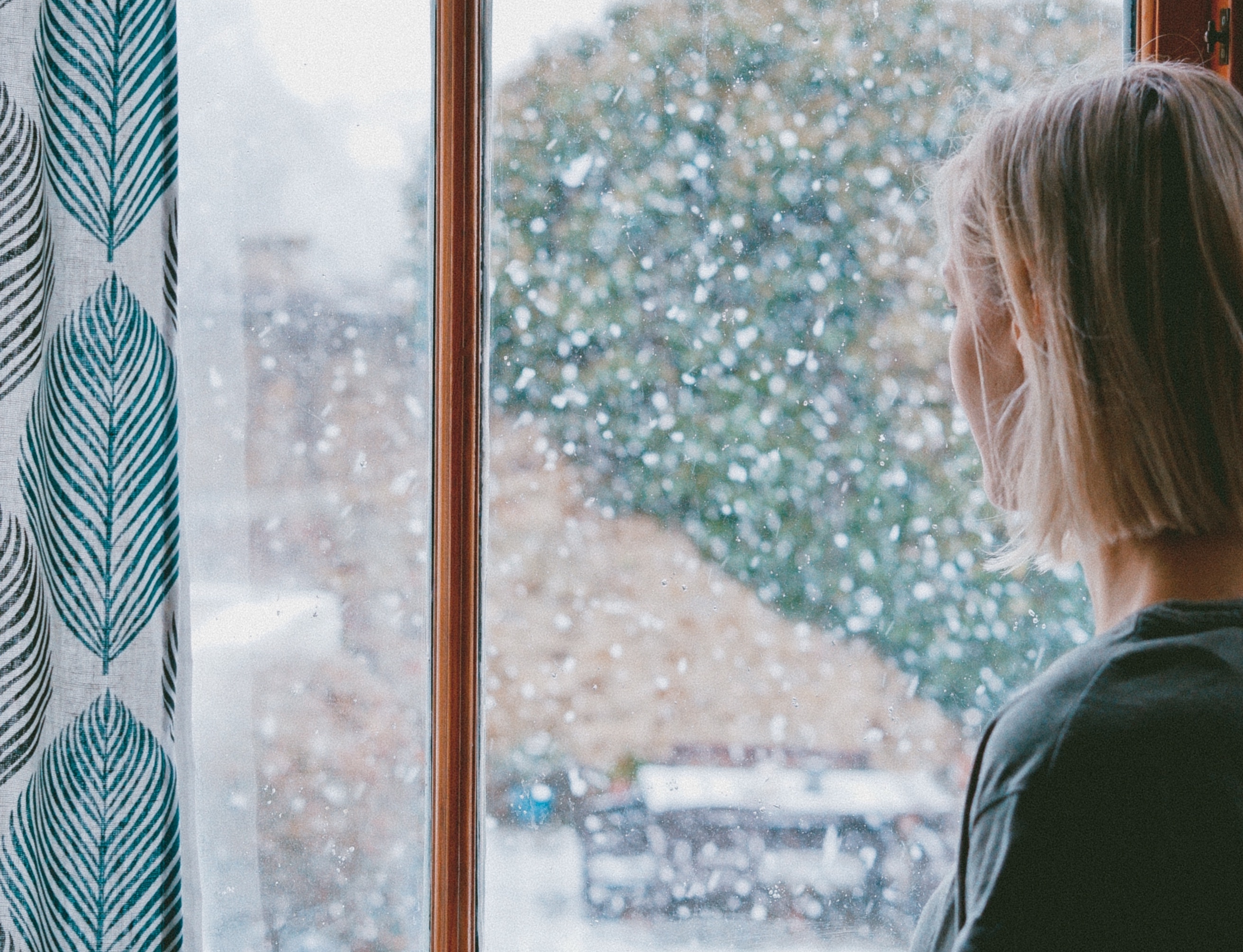 Woman looking out window at snow