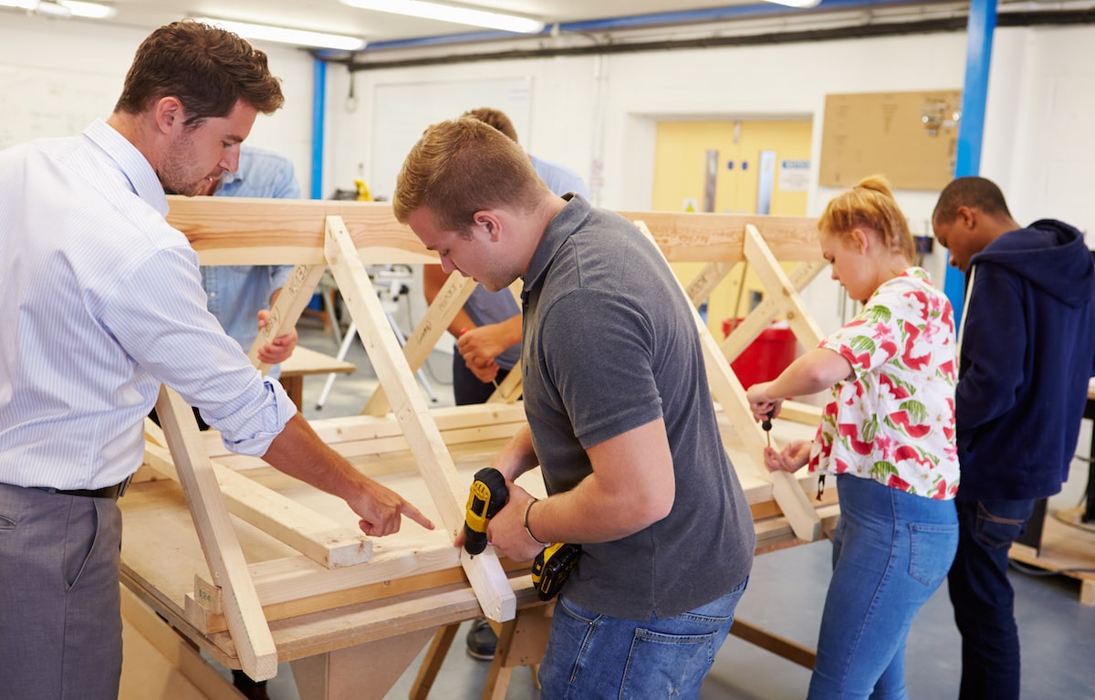 High school students building in wood shop classroom