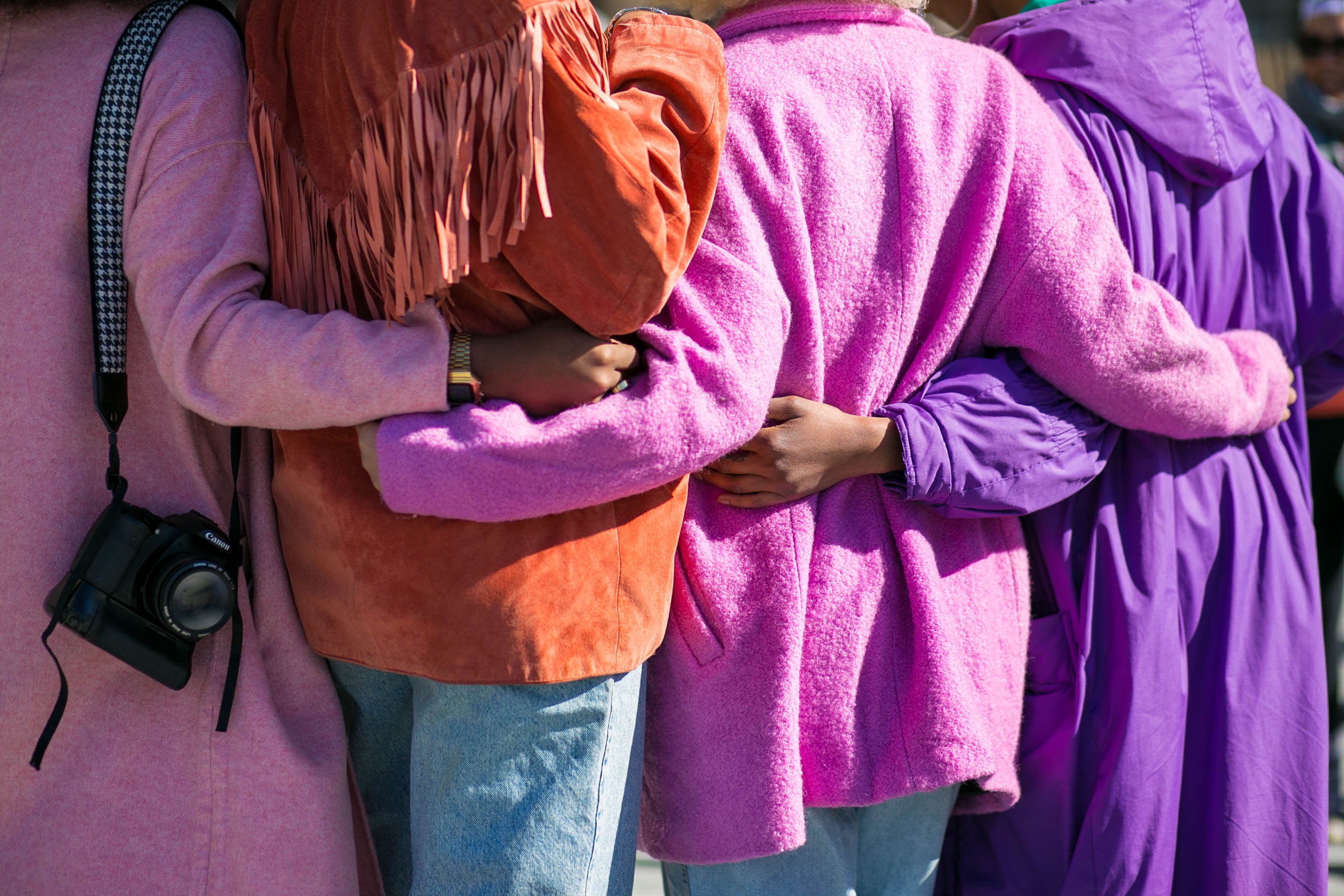 Women hugging with brightly colored coats on