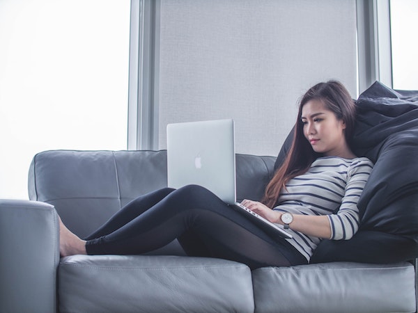 woman sitting on couch with laptop working from home