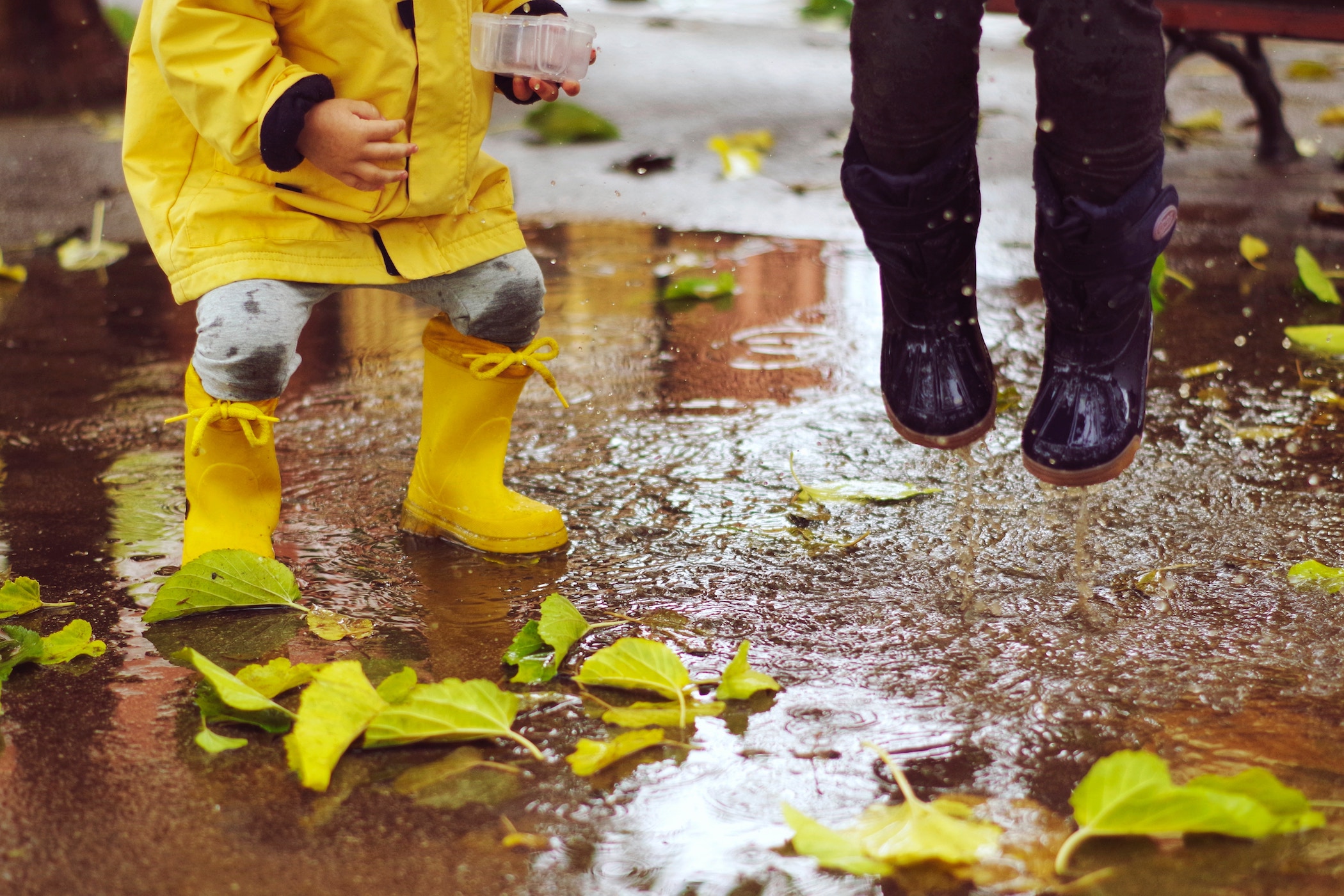 Kids in rain boots splashing in a puddle