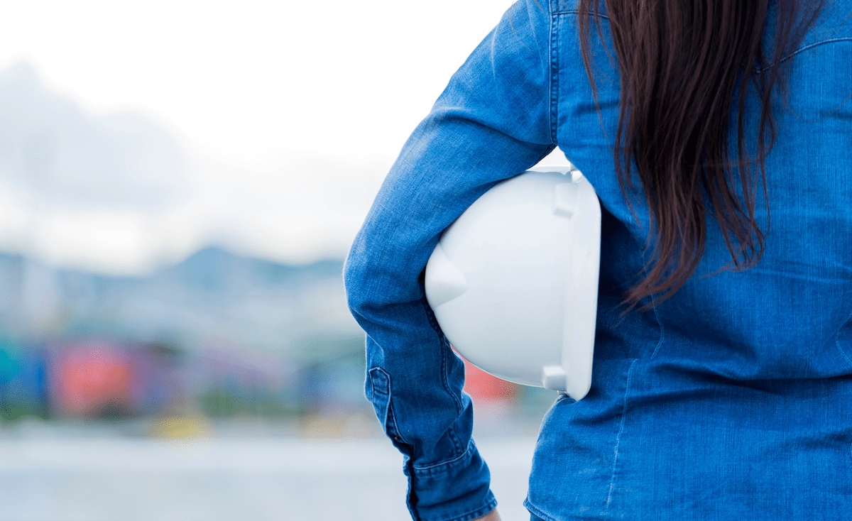 Woman construction worker holding white hardhat under her arm