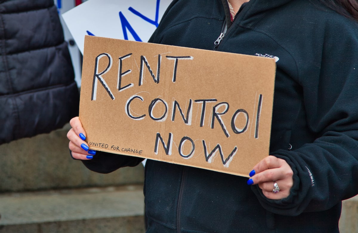 Person protesting with rent control sign