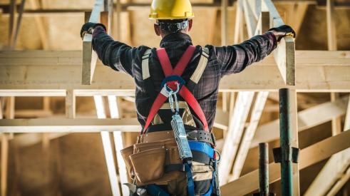 Construction worker standing amid roof trusses in house