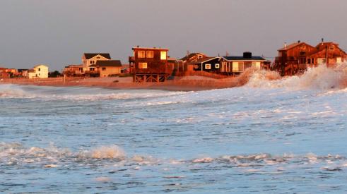 View of coastal homes at sunset from choppy sea