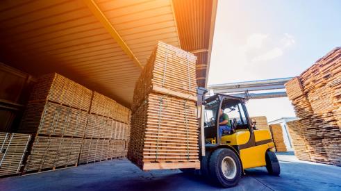 Lumber is carried through a warehouse.